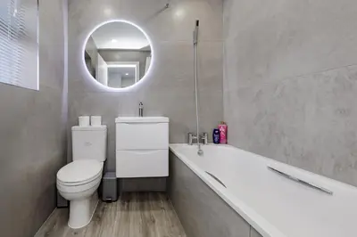 a bathroom with a toilet and a tub and a mirror at Cosy and Peaceful flat in Benfleet close to station in South Benfleet