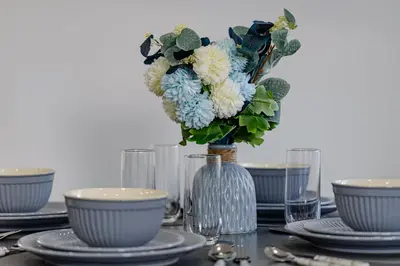 a table with plates and a vase with blue and white flowers at Cosy and Peaceful flat in Benfleet close to station in South Benfleet