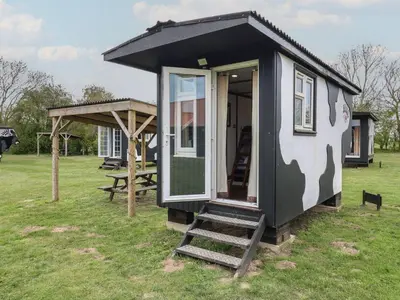 a tiny house with a staircase in a field at Molly Cow Shed 6 in Woodbridge