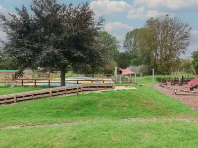 a park with a tree and a playground at Molly Cow Shed 6 in Woodbridge