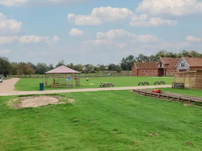a park with picnic tables and a playground at Molly Cow Shed 6 in Woodbridge