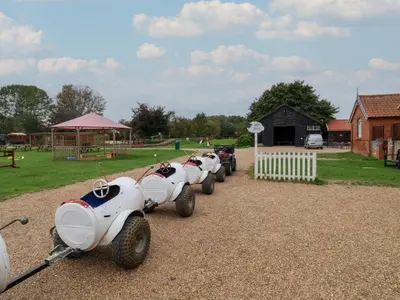 a row of white cars parked next to a park at Carabelle Cow Shed 7 in Woodbridge