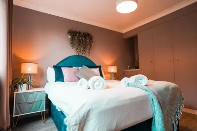a bedroom with a green bed with towels on it at Bright & Spacious 5-Bedroom Stay near Cambridge in Hardwick