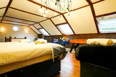 a room with two beds and a table in it at Bright & Spacious 5-Bedroom Stay near Cambridge in Hardwick