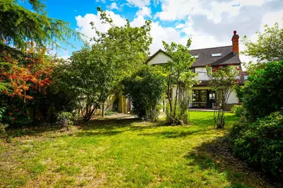a house with a yard with grass and trees at Bright & Spacious 5-Bedroom Stay near Cambridge in Hardwick
