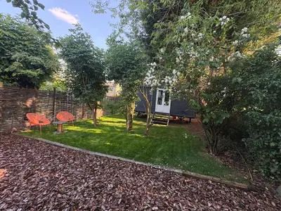 a garden with a bench and trees and a house at Shepherds hut in Holywell Cambridgeshire in Holywell