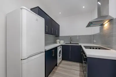 a kitchen with blue cabinets and a white refrigerator at Blue Horizon Seaside Apart in Clacton-on-Sea