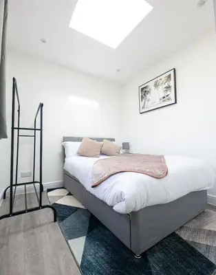 a white bedroom with a bed in a room at Jayjay Guest House in Basildon