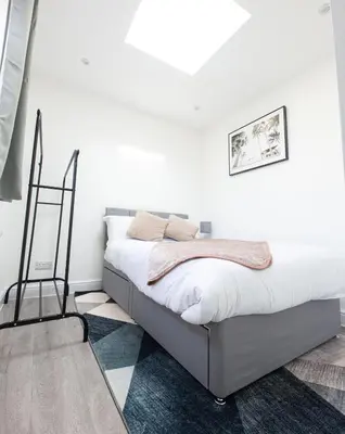 a white bedroom with a bed in a room at Jayjay Guest House in Basildon