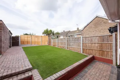 a small backyard with a green lawn at Jayjay Guest House in Basildon