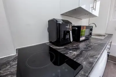 a kitchen with a black counter top with a microwave at Jayjay Guest House in Basildon