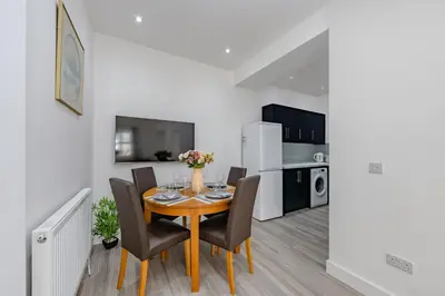 a dining room with a table and chairs and a kitchen at Triple B Aparto in Clacton-on-Sea