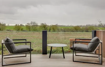 two chairs and a table on a deck with a field at Two bedroom house with far-reaching country views in Sheering