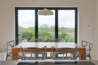 a dining room with a table and chairs and a window at Two bedroom house with far-reaching country views in Sheering
