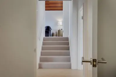 a hallway with a stairway with white walls and white stairs at Two bedroom house with far-reaching country views in Sheering