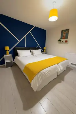 a bedroom with a large bed with a yellow and blue wall at 3 Bed Home, Sleeps 7 with Garden in Basildon in Basildon