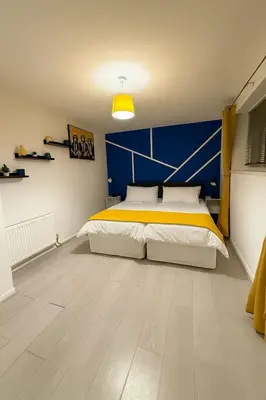 a bedroom with a large bed with a blue wall at 3 Bed Home, Sleeps 7 with Garden in Basildon in Basildon