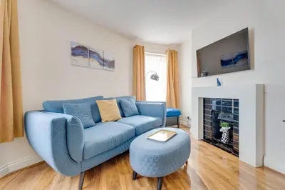 a living room with a blue couch and a tv at The Old Shoe Shop, 5 Well Lane in Clare