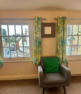 a chair sitting in a room with two windows at The Old Shoe Shop, 5 Well Lane in Clare