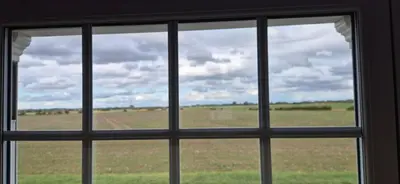 a window with a view of a field behind it at Cambridgeshire Cosy Cottage in Cottenham