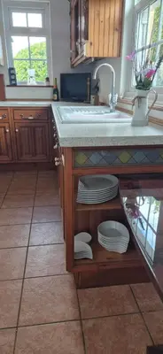 a kitchen with a sink and plates on a counter at Cambridgeshire Cosy Cottage in Cottenham