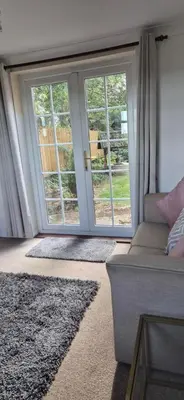 a living room with large windows and a couch at Cambridgeshire Cosy Cottage in Cottenham