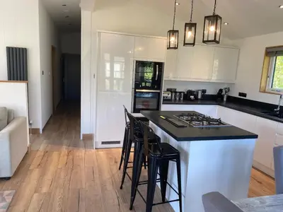 a kitchen with white cabinets and a island with bar stools at Contemporary 3 bed luxury Spa lodge with hot tub in Bury Saint Edmunds