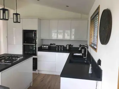 a kitchen with white cabinets and a black counter top at Contemporary 3 bed luxury Spa lodge with hot tub in Bury Saint Edmunds