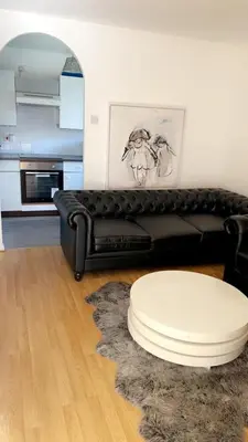 a living room with a black leather couch and a table at Home in Colchester in Colchester