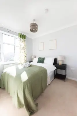 a white bedroom with a large bed with green sheets at 4 Bedroom Home - 2 Mins to Town CM7 - Contractor Ready in Braintree