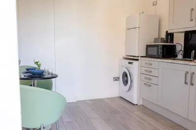 a kitchen with a washing machine and a table at Luxury Five-Bedroom Home with Jacuzzi and Gym - Private One-Bedroom Garden Suite Available Separately in Basildon