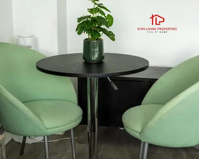a table with two green chairs and a potted plant at Luxury Five-Bedroom Home with Jacuzzi and Gym - Private One-Bedroom Garden Suite Available Separately in Basildon