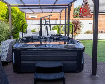 a hot tub on a deck with a table and chairs at Luxury Five-Bedroom Home with Jacuzzi and Gym - Private One-Bedroom Garden Suite Available Separately in Basildon