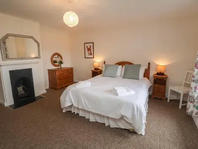 a bedroom with a large bed and a fireplace at Duke Cottage in Woodbridge