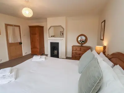 a bedroom with a large white bed and a fireplace at Duke Cottage in Woodbridge