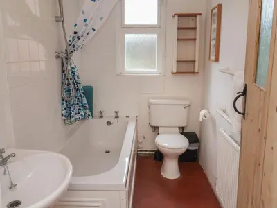 a bathroom with a toilet and a tub and a sink at Duke Cottage in Woodbridge