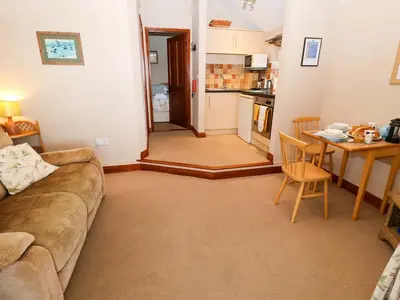 a living room with a couch and a table and a kitchen at Hayloft in Ipswich