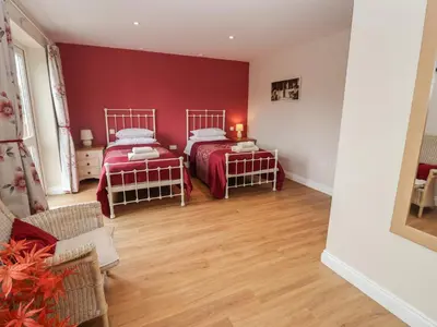 two beds in a room with red walls and wooden floors at Fisherman's Rest in Ipswich