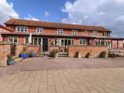 a brick house with a courtyard in front of it at Coachman's Cottage in Ipswich