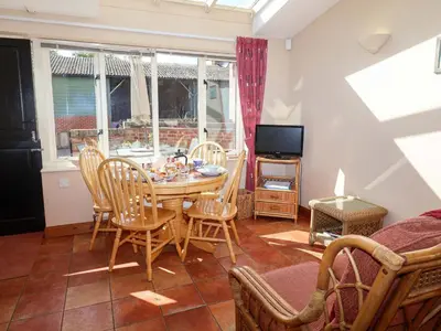 a dining room with a table and chairs and a television at Coachman's Cottage in Ipswich