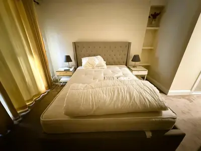 a large bed in a bedroom with two night stands at Elegant 5BDR Executive Home Chigwell in Chigwell