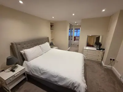 a bedroom with a white bed and a mirror at Elegant 5BDR Executive Home Chigwell in Chigwell