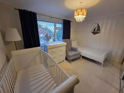 a room with a crib and a bed and a window at Elegant 5BDR Executive Home Chigwell in Chigwell