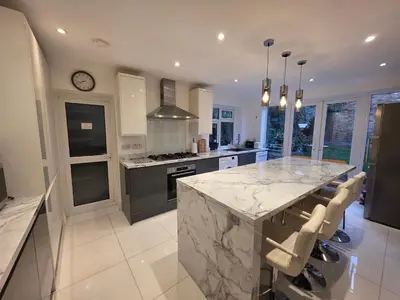 a kitchen with a marble counter top and a large island at Elegant 5BDR Executive Home Chigwell in Chigwell