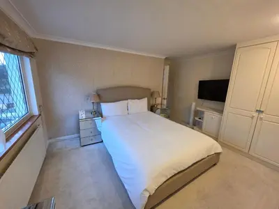 a bedroom with a bed and a flat screen tv at Elegant 5BDR Executive Home Chigwell in Chigwell