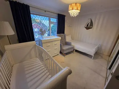 a room with a crib and a chair and a window at Elegant 5BDR Executive Home Chigwell in Chigwell