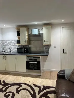 a kitchen with white cabinets and a black counter top at A Cosy and Spacious Studio Flat in Navestock