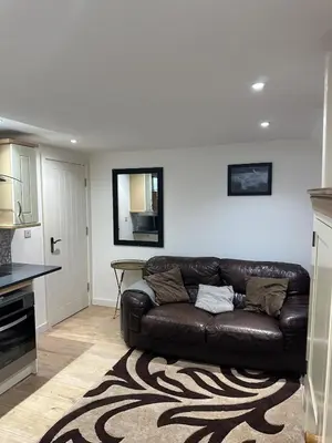 a living room with a brown leather couch in a kitchen at A Cosy and Spacious Studio Flat in Navestock