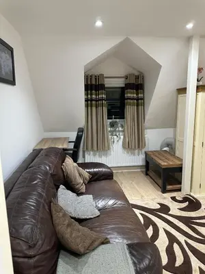 a living room with a brown leather couch at A Cosy and Spacious Studio Flat in Navestock