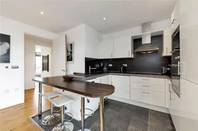 a kitchen with white cabinets and a wooden table at The Luxurious Penthouse in Cambridge